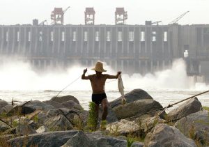 A Chinese man carries a fish he caught below the spillway of the Three Gorges Dam on the Yangtze River, near Yichang, in central China's Hubei province Friday June 13, 2003. Chinese officials have admitted Thursday there are about 80 cracks in the dam, the world's largest, which could cause leaks if not fixed. (AP Photo/Greg Baker)